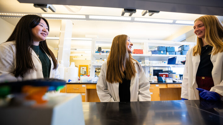 Husker undergraduates and UCARE participants (from left) Chanasei Ziemann, Vanessa Hubing and Avery Marquis pose in lab coats for a photo in Luwen Zhang’s campus lab.