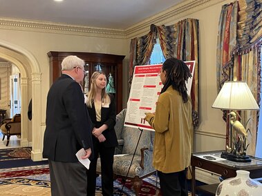 students showing research poster at governor's mansion