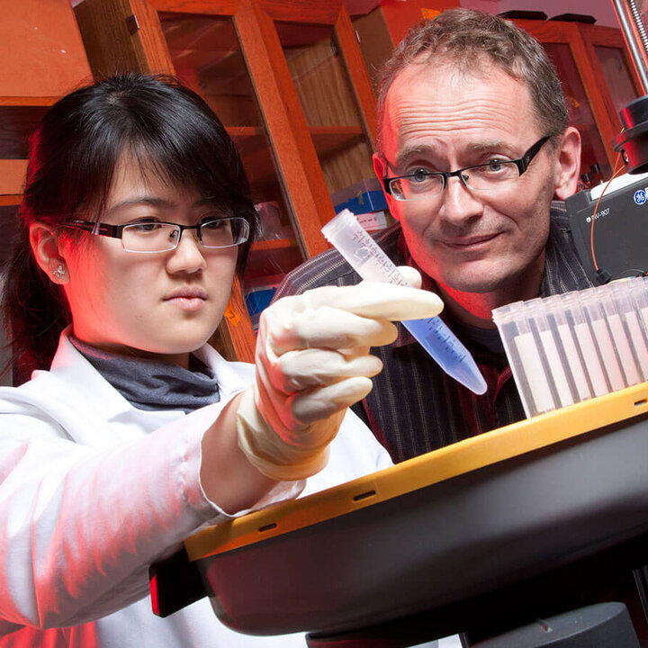 student in white coat in biological science lab with instructor